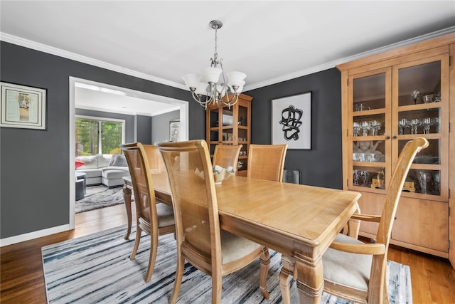 dining room with crown molding, baseboards, wood finished floors, and a chandelier