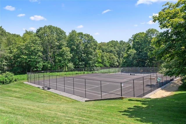 view of tennis court featuring a yard and fence