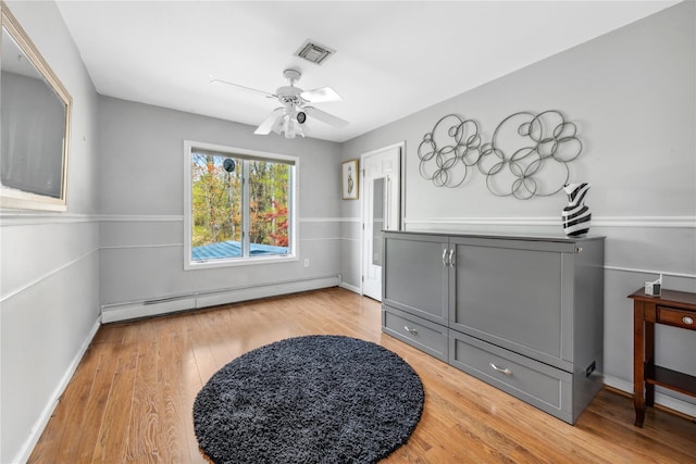 sitting room with ceiling fan, visible vents, baseboard heating, baseboards, and light wood-style flooring