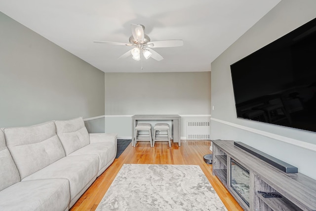 living room featuring wood finished floors, ceiling fan, and radiator