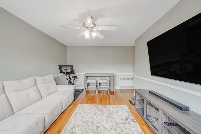 living area featuring radiator heating unit, wood finished floors, and ceiling fan