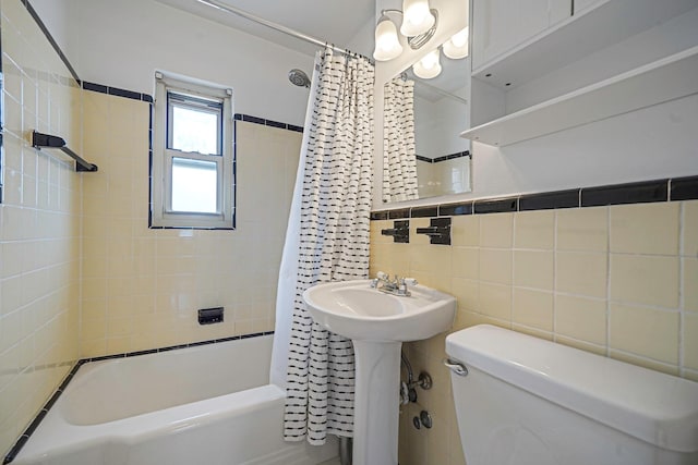 full bathroom featuring tile walls, toilet, shower / bath combo, and a sink