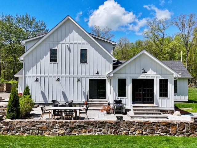 back of property featuring board and batten siding, entry steps, a patio, and a shingled roof