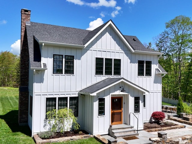 modern farmhouse with a chimney, board and batten siding, a shingled roof, and entry steps