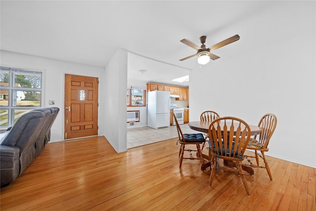 dining space with ceiling fan, baseboards, and light wood-style flooring