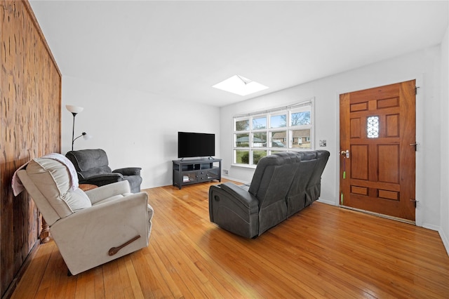 living area featuring light wood-style flooring and a skylight