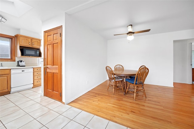 dining space with ceiling fan, light wood finished floors, and a skylight