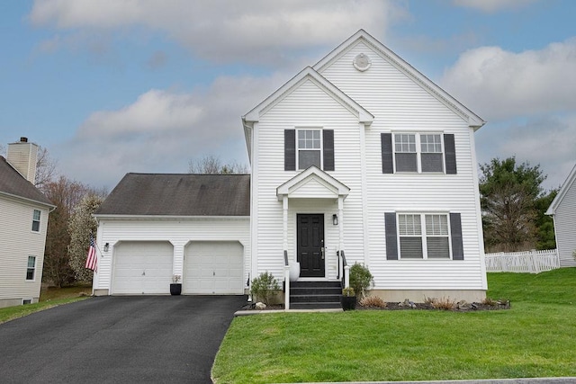traditional-style home with fence, driveway, a front yard, and a garage