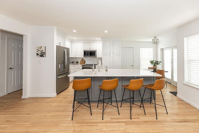 kitchen with white cabinets, light wood-type flooring, baseboards, and stainless steel appliances