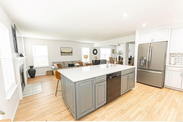 kitchen featuring white cabinets, light wood finished floors, stainless steel appliances, and gray cabinetry