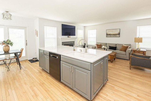 kitchen featuring dishwasher, a sink, light wood-style floors, gray cabinetry, and open floor plan