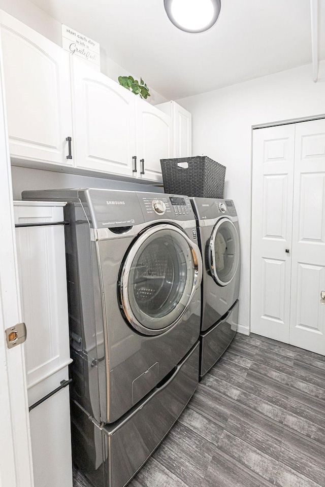 laundry room featuring washing machine and dryer, dark wood finished floors, and cabinet space