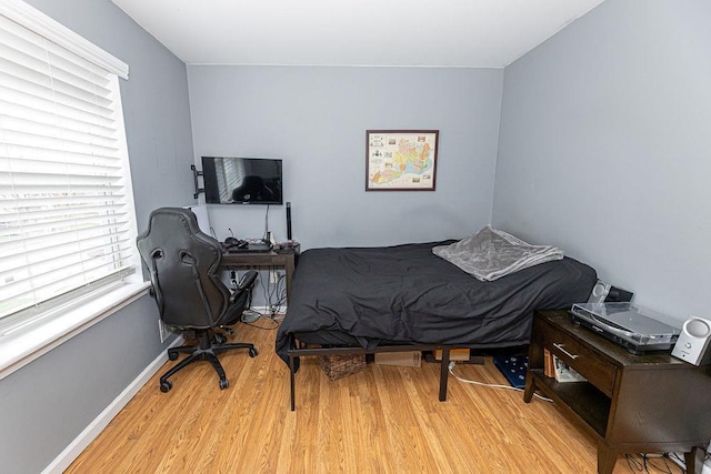 bedroom with multiple windows and wood finished floors