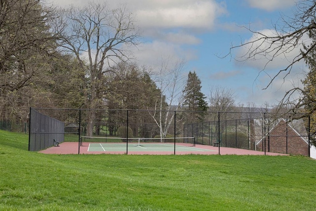 view of sport court with a lawn and fence