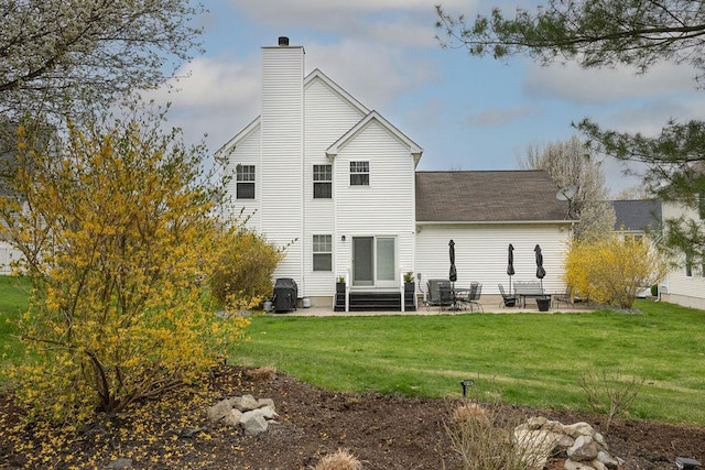back of property featuring roof with shingles, a chimney, entry steps, a lawn, and a patio