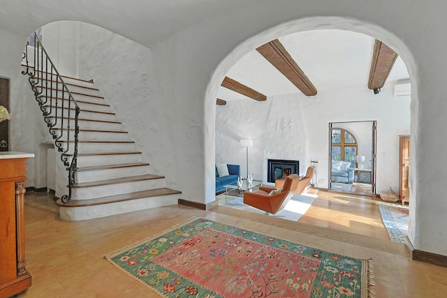 living area featuring an AC wall unit, arched walkways, a fireplace, and stairway