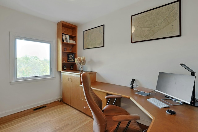 office area with baseboards, visible vents, and light wood finished floors