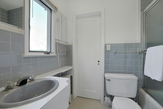 full bathroom featuring toilet, tile walls, shower / bath combination with glass door, and vanity