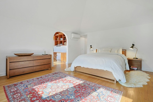 bedroom with baseboards, wood finished floors, and a wall mounted air conditioner