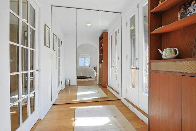 corridor with recessed lighting, french doors, and light wood-style floors