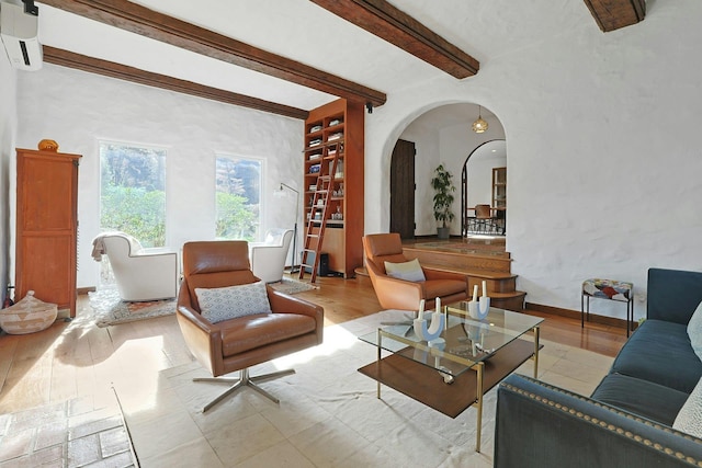 living area with arched walkways, baseboards, wood finished floors, beamed ceiling, and a wall mounted AC