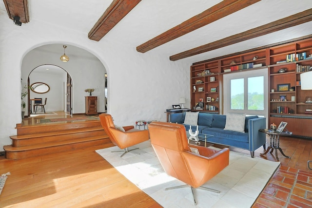 living room featuring stairway, arched walkways, and beamed ceiling