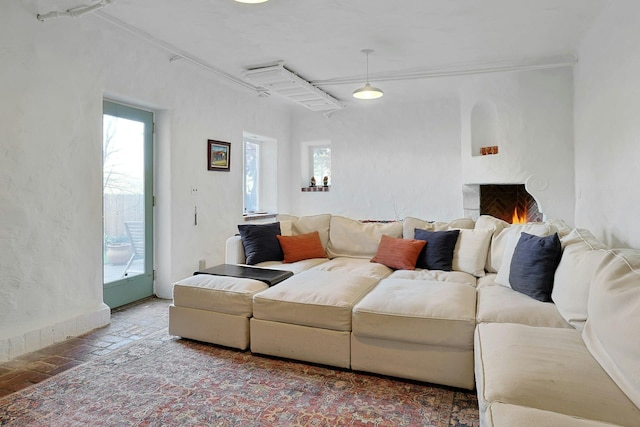 living area featuring brick floor and a warm lit fireplace
