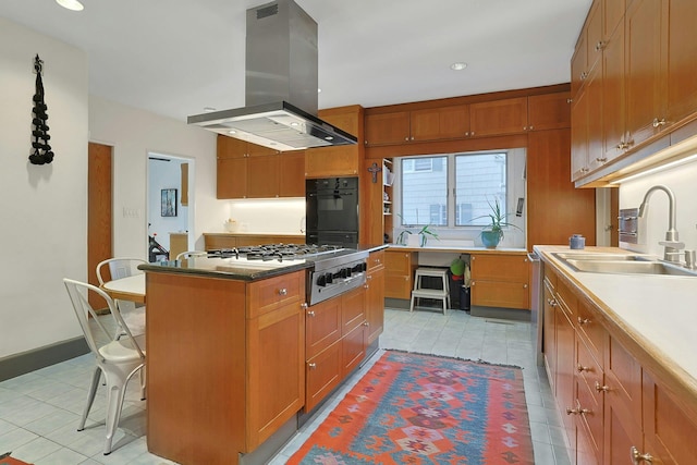 kitchen featuring a sink, light tile patterned floors, stainless steel gas stovetop, island range hood, and a kitchen island