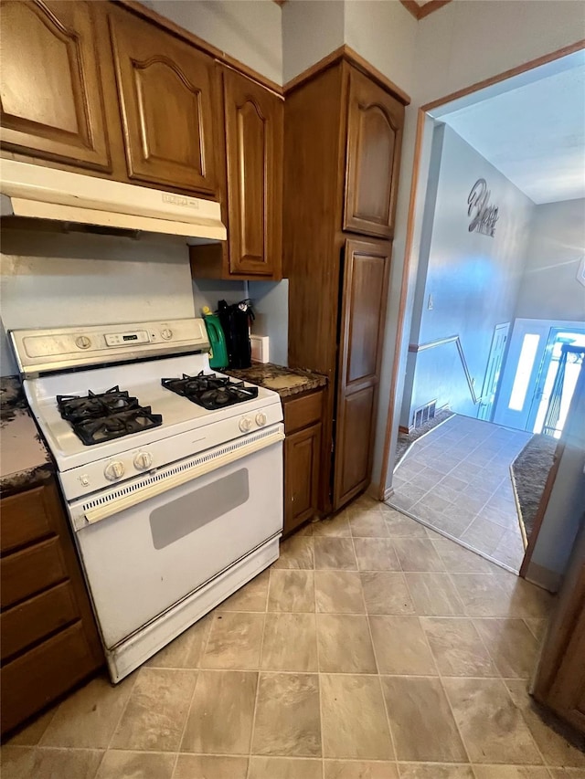 kitchen featuring visible vents, under cabinet range hood, white range with gas stovetop, and brown cabinets