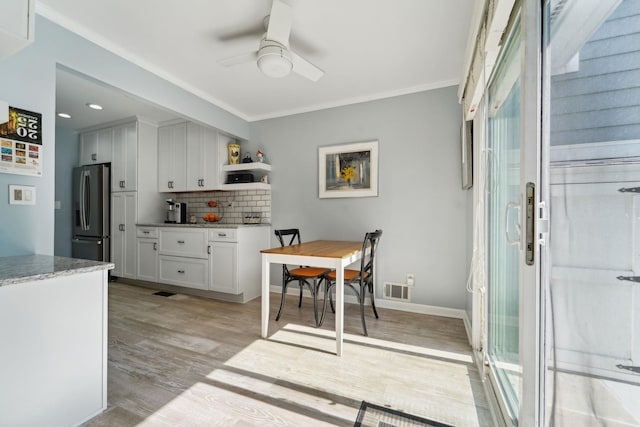 kitchen with decorative backsplash, ceiling fan, visible vents, stainless steel fridge, and light wood-style flooring