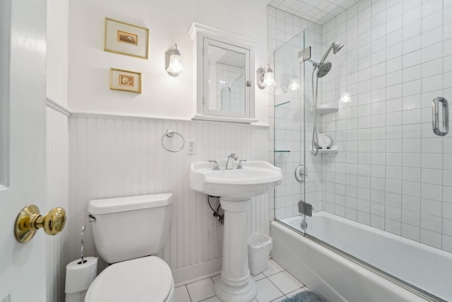 bathroom featuring  shower combination, wainscoting, tile patterned floors, and toilet