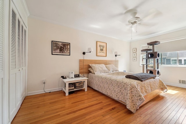 bedroom with crown molding, light wood finished floors, baseboards, and a closet