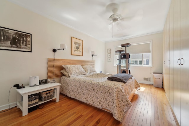 bedroom featuring crown molding, ceiling fan, light wood finished floors, baseboards, and visible vents