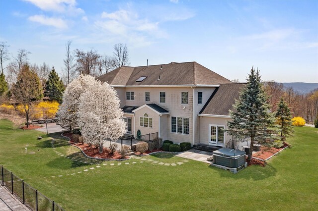 back of property featuring fence, a lawn, roof with shingles, and a patio area