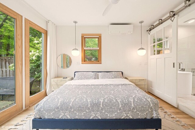 893 Laroe Rd, Monroe, NY 10950 - bedroom featuring a wall mounted AC, wood finished floors, a barn door, and ceiling fan