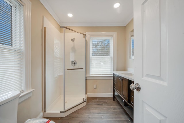 bathroom featuring toilet, vanity, ornamental molding, wood finish floors, and a stall shower