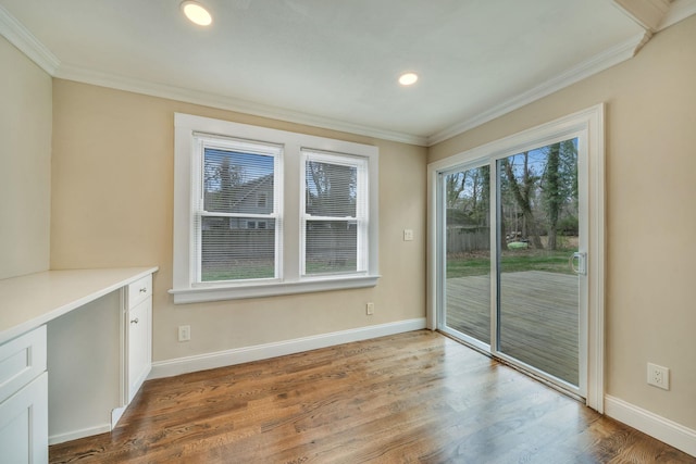 unfurnished dining area featuring baseboards, crown molding, and wood finished floors
