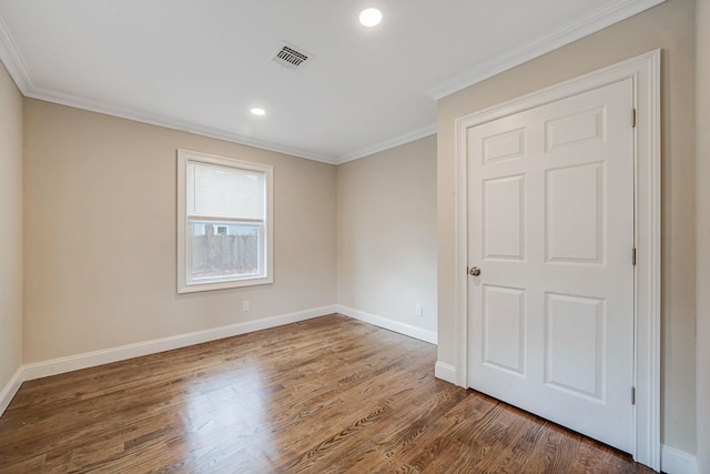 interior space with baseboards, ornamental molding, wood finished floors, and visible vents