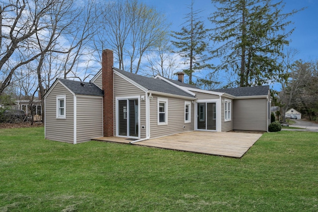 rear view of property with a shingled roof, a chimney, a yard, and a deck