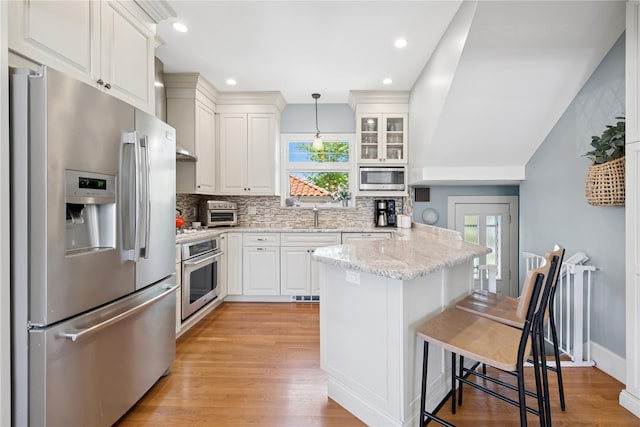 kitchen with a kitchen breakfast bar, appliances with stainless steel finishes, a wealth of natural light, and a sink