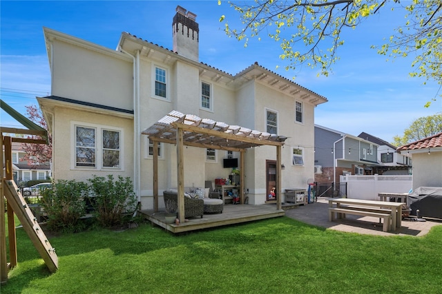 rear view of house with fence, a pergola, a deck, stucco siding, and a chimney