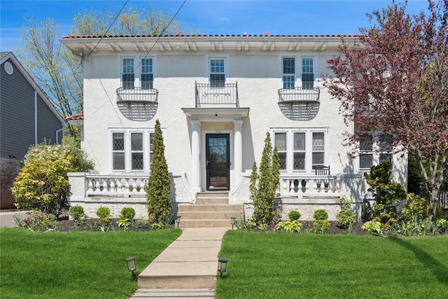 view of front of property with a front lawn, stucco siding, and a balcony