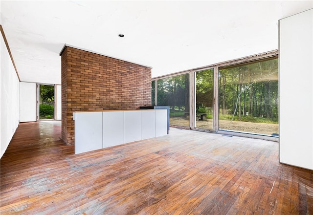 319 Pound Ridge Rd, Bedford, NY 10506 - unfurnished living room featuring hardwood / wood-style floors, brick wall, and expansive windows