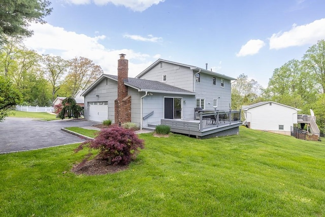 26 Strathmore Dr, New City, NY 10956 - rear view of property featuring driveway, a deck, a chimney, an attached garage, and a yard