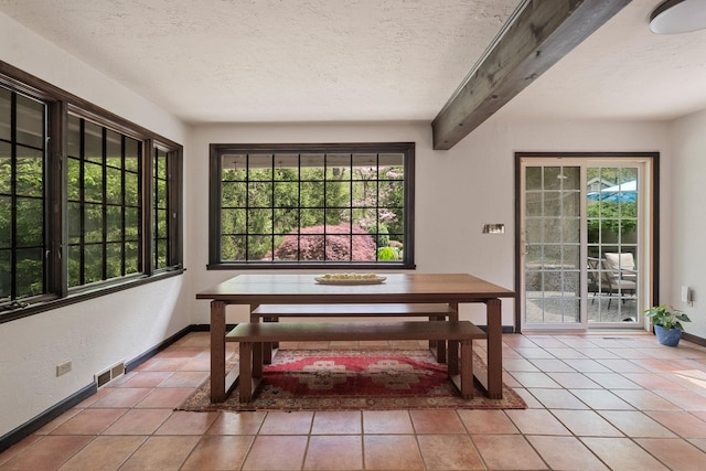 tiled dining space featuring baseboards, beam ceiling, and a textured ceiling