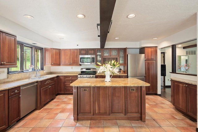 kitchen featuring a center island, a sink, stainless steel appliances, light stone countertops, and recessed lighting