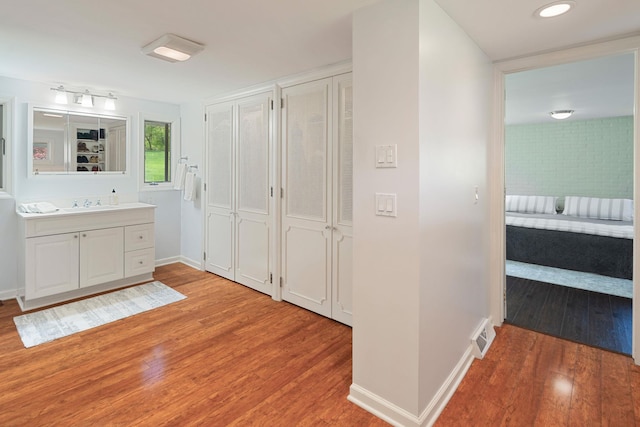 bathroom with a closet, baseboards, wood finished floors, and vanity