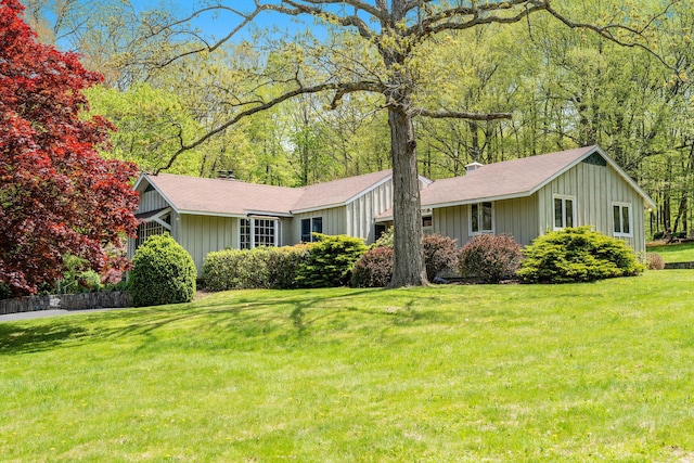 ranch-style house with board and batten siding, roof with shingles, and a front yard