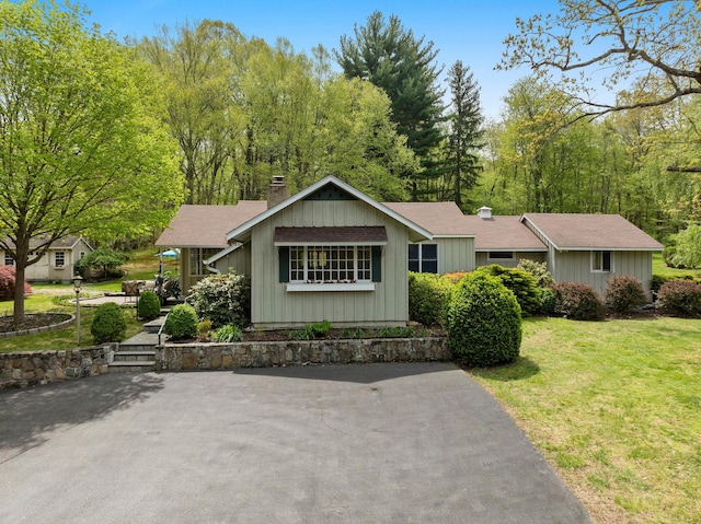 single story home with roof with shingles, a chimney, and a front yard