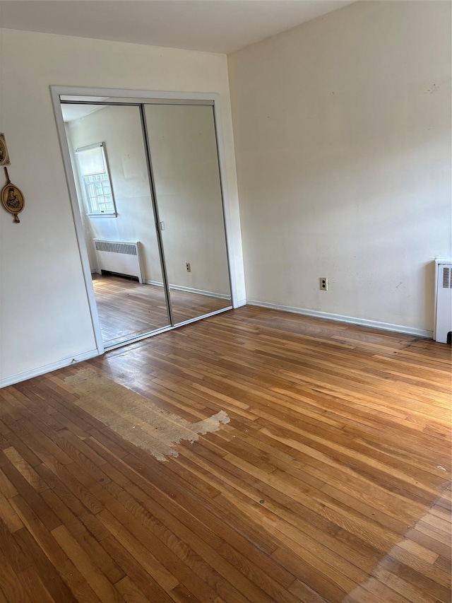 8 Dee Pl, Huntington Station, NY 11746 - unfurnished bedroom featuring wood-type flooring, baseboards, radiator heating unit, and a closet
